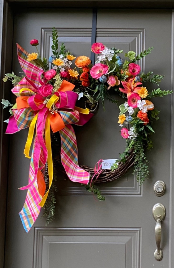 PinkYellow Door Wreath product image features a colorful wreath.  24-inch grapevine frame.  Faux flowers and greenery.  Pinks, yellows, blue, orange and white.  Large designer bow.   Measures 28"WX 36"H.  Indoor or outdoor use under an overhang.