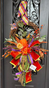 Autumn Wreath with a pumpkin, flowers , mixed greenery, and a beautiful hand tied bow in shades of orange, purple and a hint of yellow.
