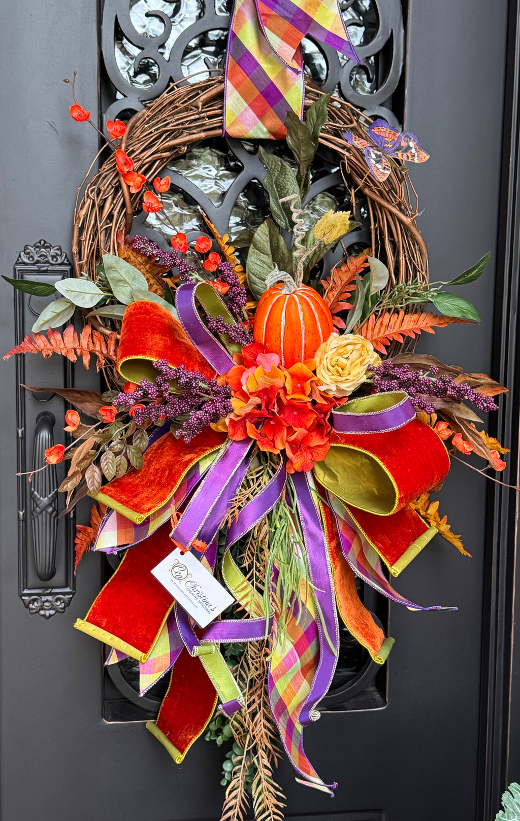 Autumn Wreath with a pumpkin, flowers , mixed greenery, and a beautiful hand tied bow in shades of orange, purple and a hint of yellow.