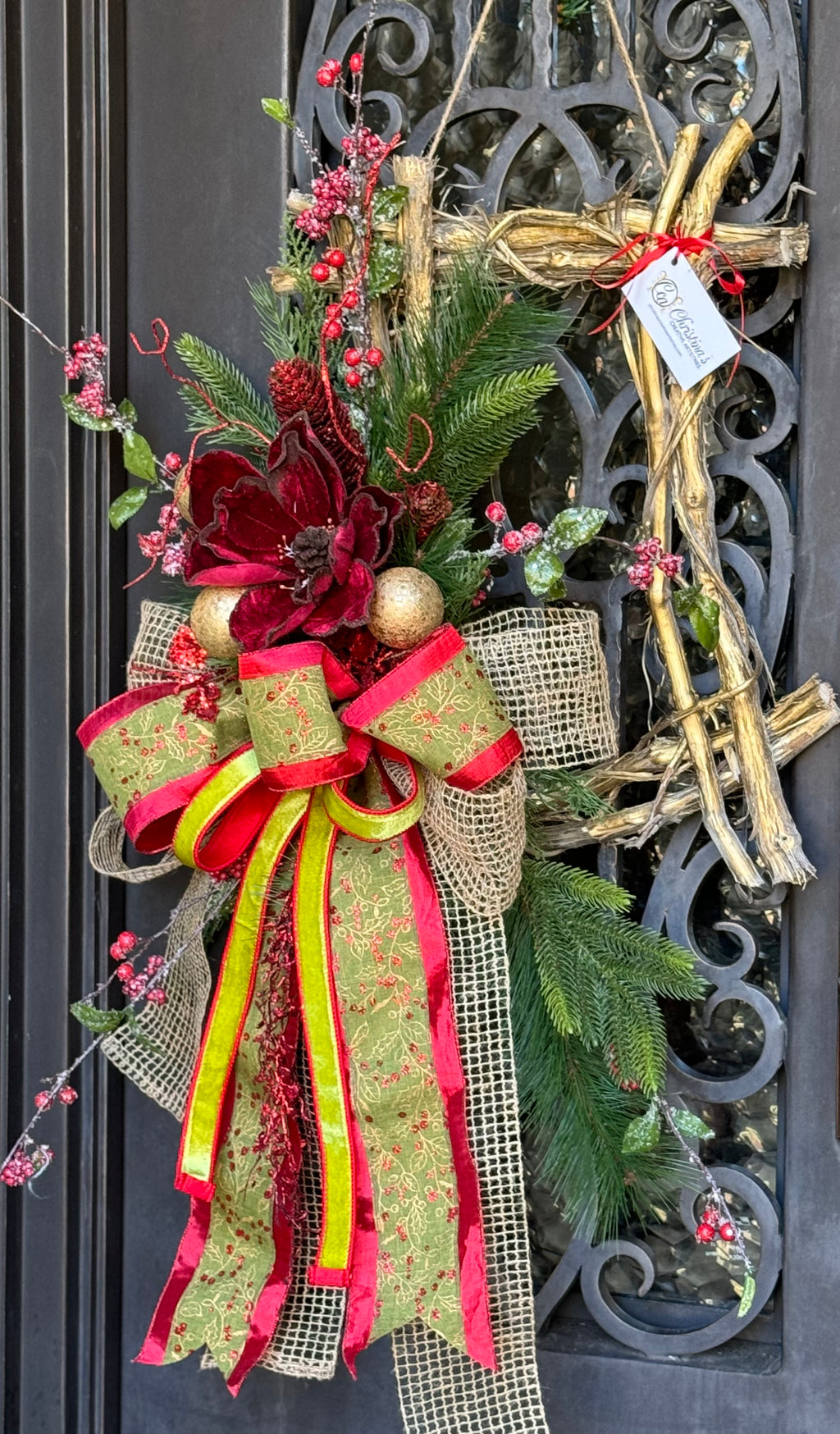 Magnolia Wreath product image features door wreath.  Christmas Winter Wreath. Colors: Red, green, 24K gold , natural.  Materials: vine frame, faux greenery, frosted berries, ball ornaments.   Use indoor/outdoor. Measures: 45"H X 24"W.  Comes ready to hang.