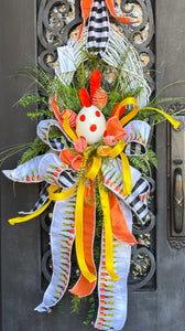 Easter Egg Wreath features an oval door wreath.  White-washed grapevine frame.  Faux egg, carrots flowers and faux greenery.  Colors are orange, yellow and white.  Measures 50"H X 21"W.   Comes ready to hang on a wreath hanger, hook or nail.