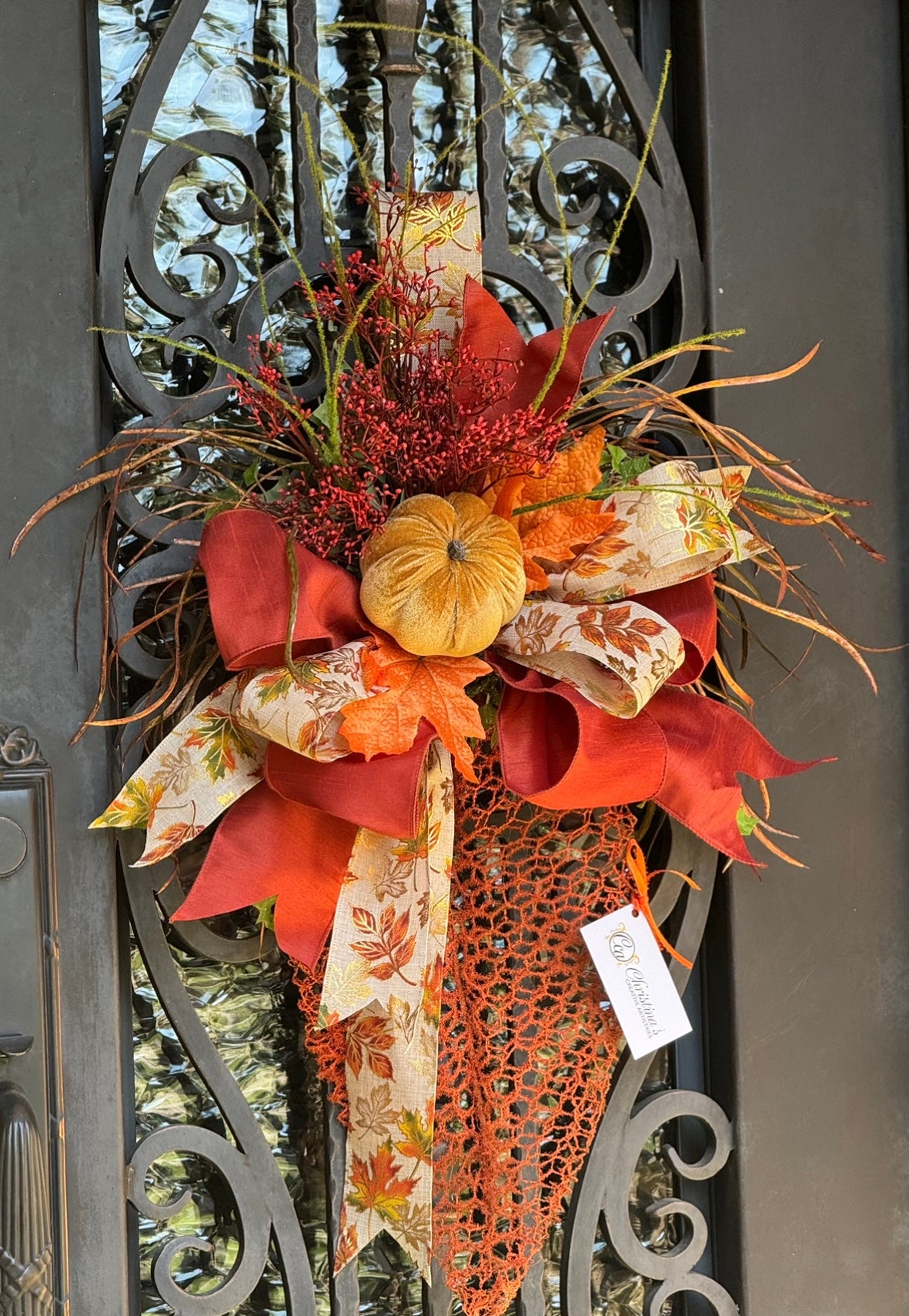 Fall Leaf Door Decor product image features a fall pumpkin wreath.  Color:Burnt orange and gold.  Materials: Metal, velvet, faux silks.  Measures: 35”H X 20”W.  Indoor/outdoor.  Two available for double doors.  Comes ready to hang.