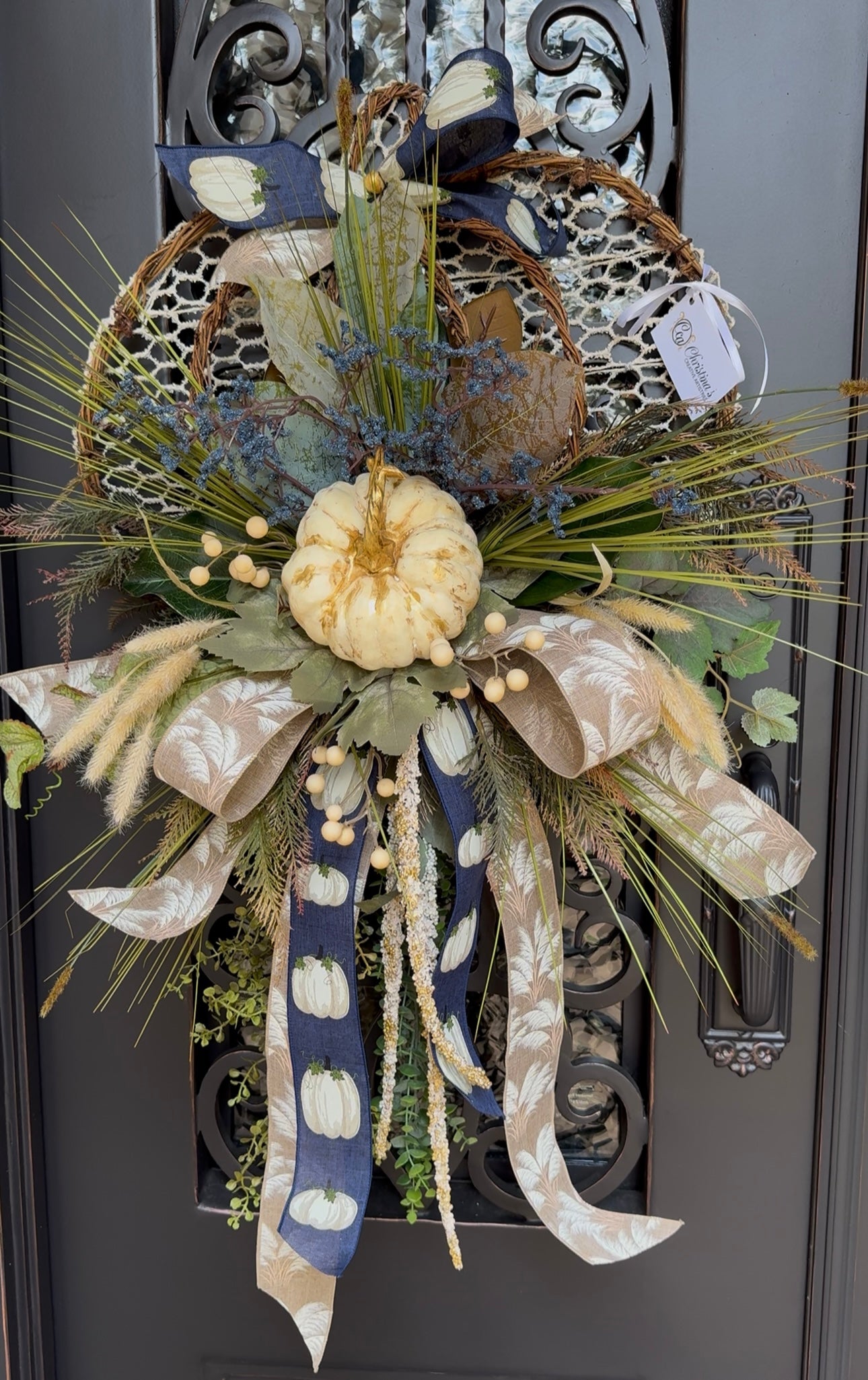 Decorative wreath with pumpkins, ribbons, and foliage on a door.  Measures 40"H X 26" W