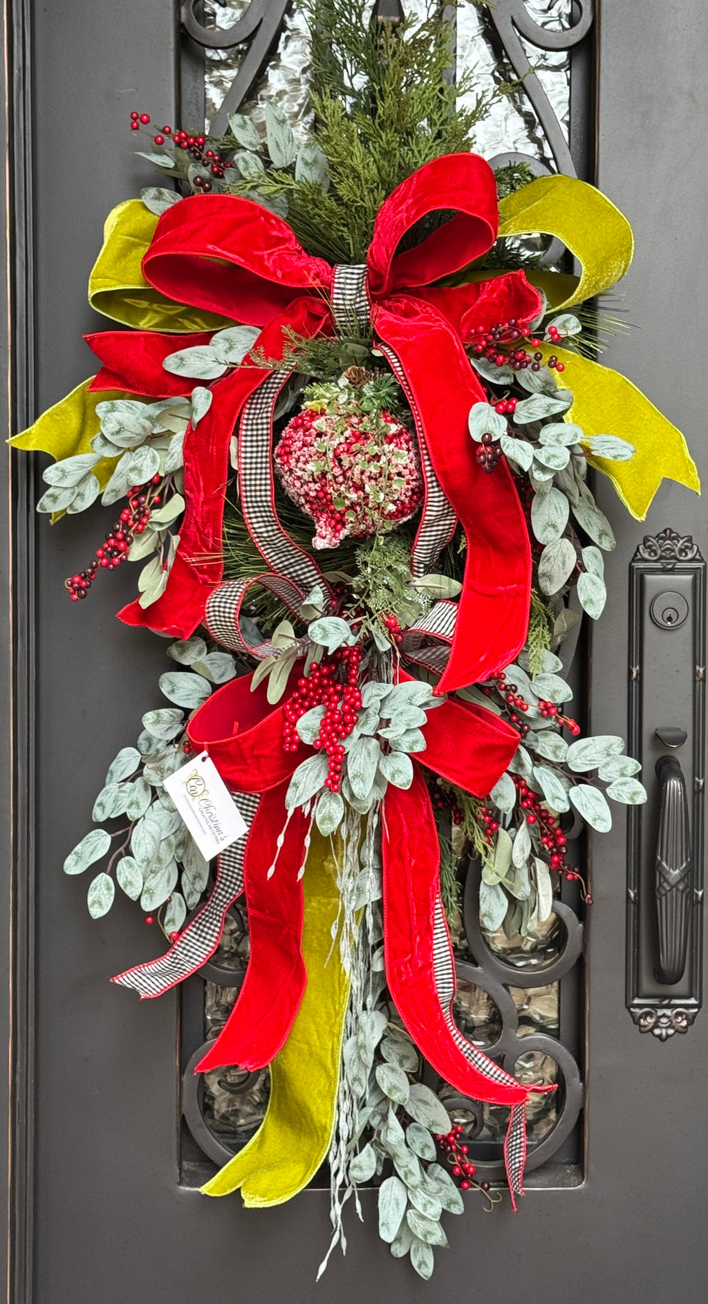 Decorative swag with red, black and white, and chartreuse ribbons on a door