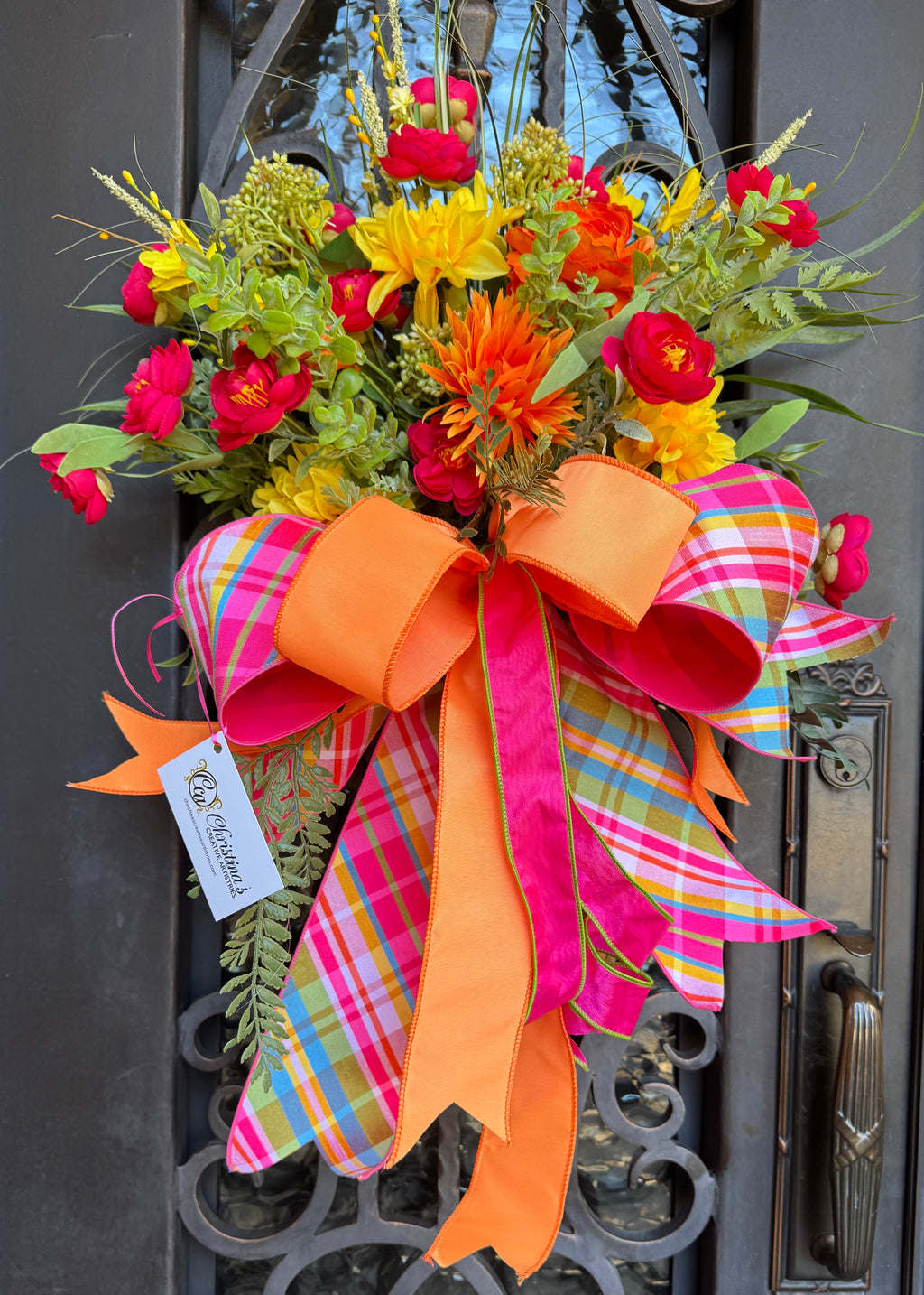 Spring Summer Door Basket.  Door basket with lifelike flowers.  Large wired bow.  Colors are hot pink, orange and yellow.  Indoor use.  Outdoor use under an overhang.  Measures 27.5" H X 20" W.