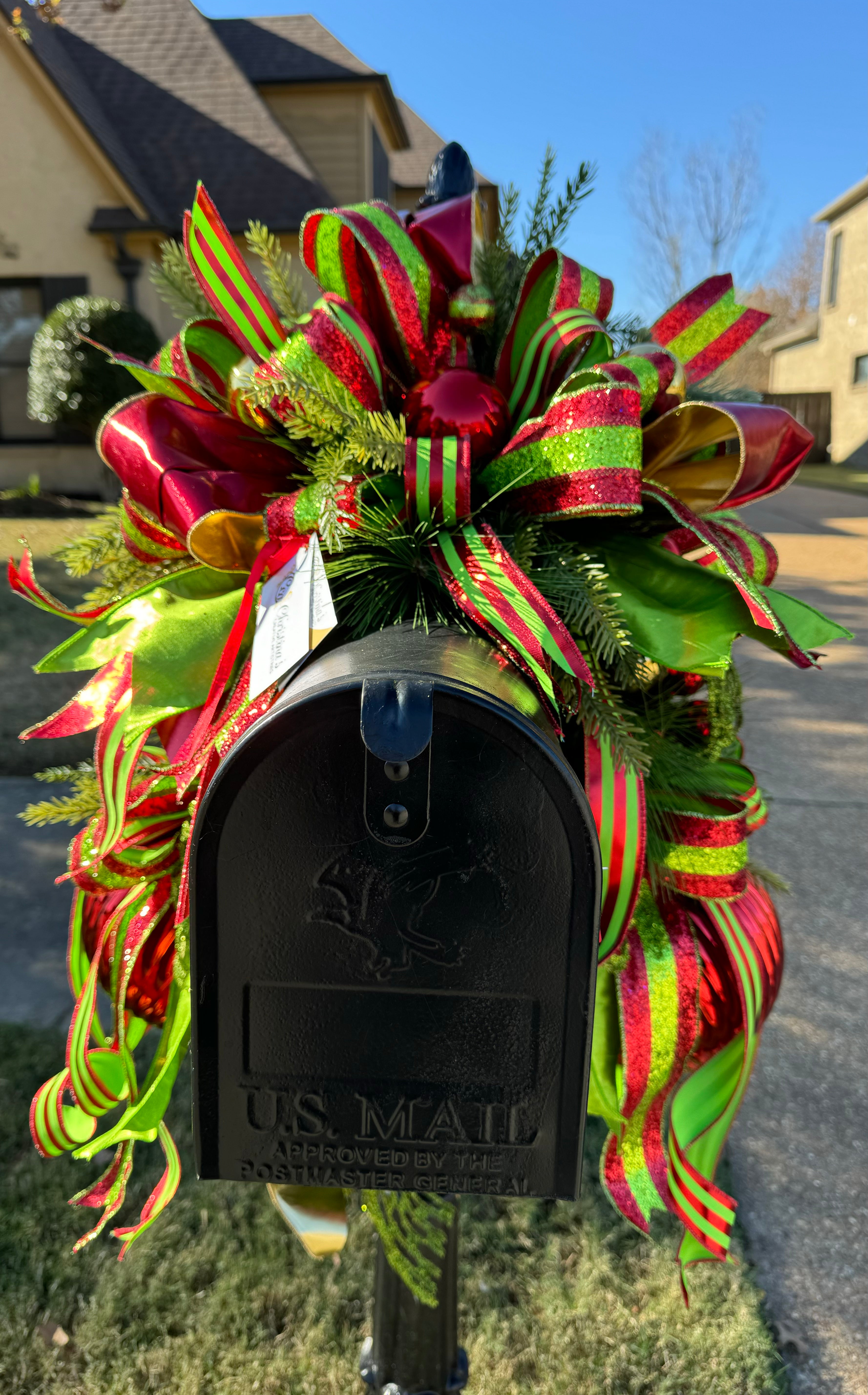 Christmas Mailbox Swag product image features a Mailbox Christmas Decoration Colors:  Red, gold, lime green.  Materials: large ornaments, faux greenery,  designer  ribbons.  Outdoor use.  limited edition 
 Exclusive .