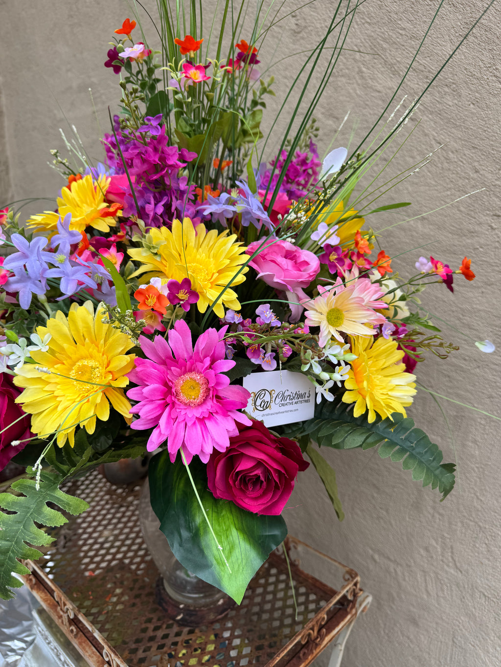 Graveside floral   Faux flowers and greenery.  Pinks, yellow, purple.  Measures about 40 “ h