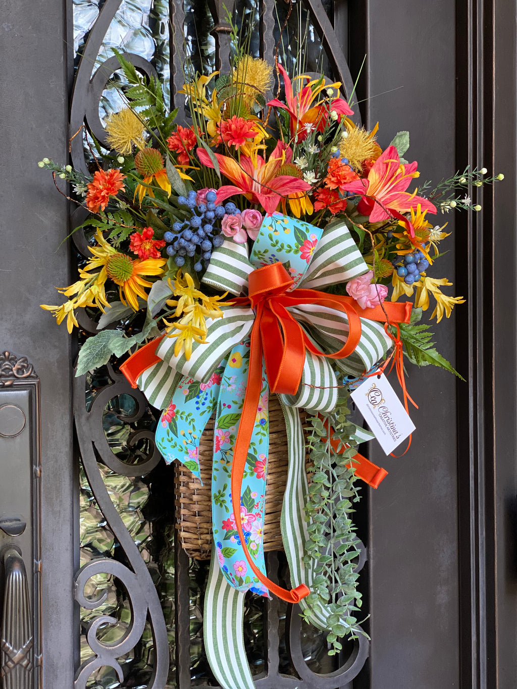 Summer Door Basket product image features a door basket.  Handmade.  Colorful.  Rattan basket filled with flowers and berries . Colors are orange, yellow, white, blue and pink.  large bow. Faux flowers. Indoor outdoor.  Measures 36"H X 20.5"W.  Comes ready to hang under an overhang.