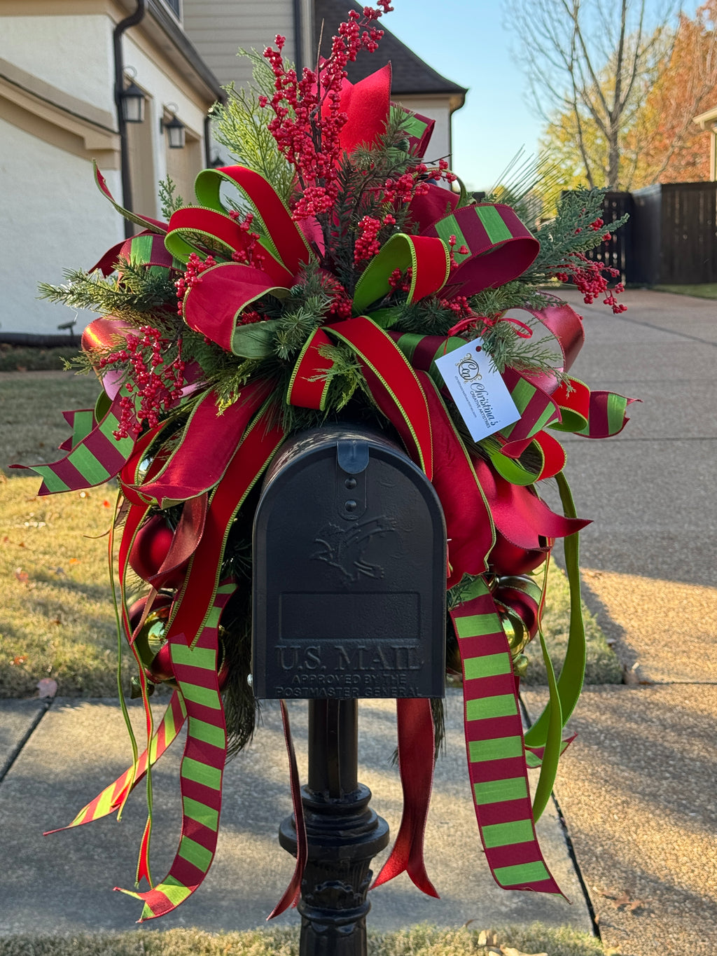 Decorative mailbox swag with red berries, shatterproof ornaments , and red and green ribbons on a standard mailbox.