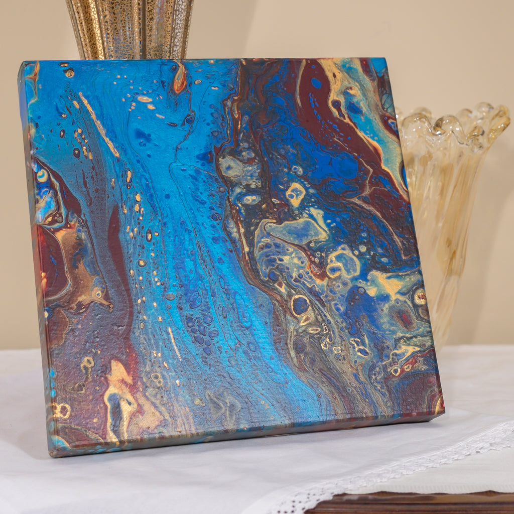 Pacific Jewel by Christina Russell features original artwork.  One-of-a-kind .  Acrylics in dark red, gold and metallic blue.  Measures 12” x12”.  Wrapped Canvas.  Modern. Comes ready to hang