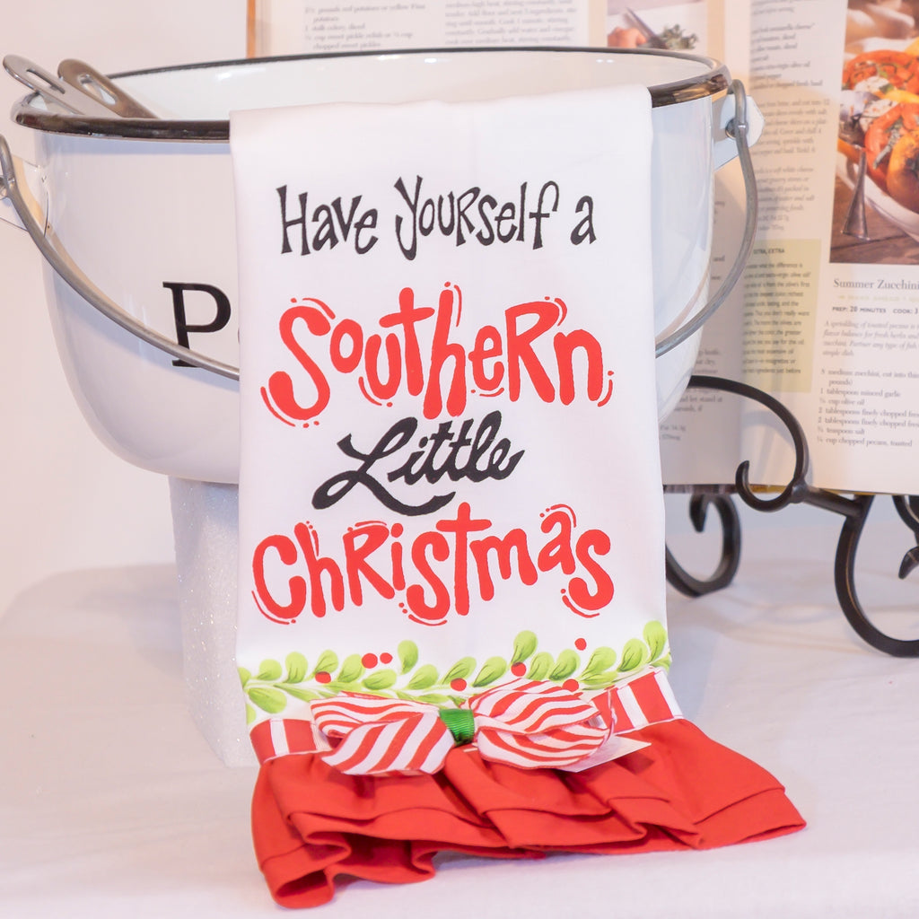 Holiday Themed Tea Towel product image features a white cotton tea towel with " Have yourself a Southern Little Christmas"  written in black and red lettering.  This tea towel has a red pleated bottom with a red and white striped bow.  Stocking stuffer.  Housewarming gift.  Hostess gift.  Christmas gift.  Kitchen decor.