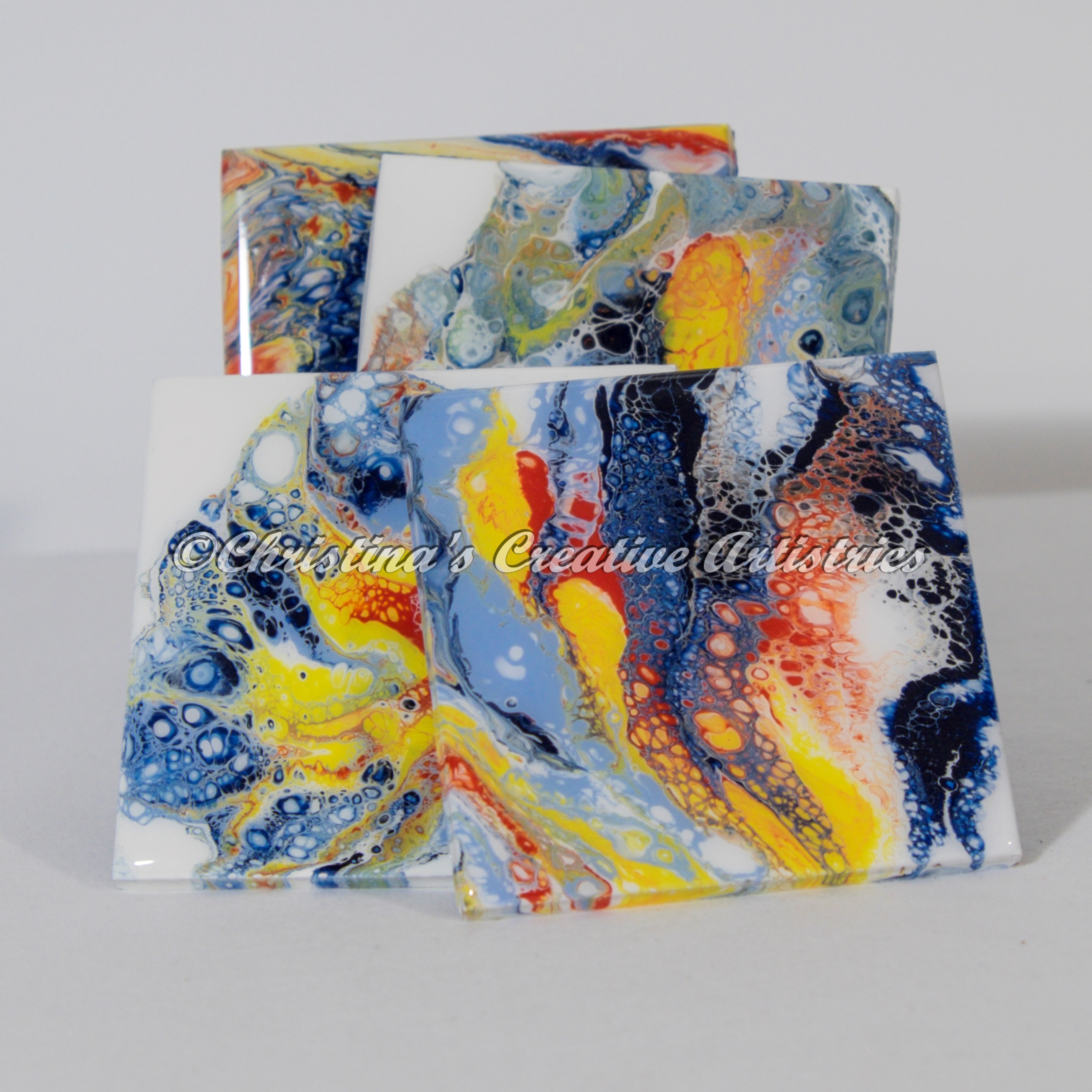 Color Dramaz product image features a set of 4 coasters. 4" x 4" Ceramics.  Hand painted.  Medium: acrylics.  Colors: light blue, dark blue, yellow, orange, white.  Durable coating.  Cork backed.   Clear acrylic coaster stand included.  Art on tile. Perfect for holding your cold drinks.   Protects your table tops from watermarks. 