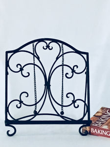 Scroll pattern Iron Cookbook Stand.  Elegant, beautiful and decorative.  Fixture includes two small weighted chains with ball finials used to hold open pages.  Ideal for displaying cookbooks and recipes.  Measures 12.4"Wx8.05"Dx14"H.   Holds up to 8 Ibs.  Dark mahogany color.  This cookbook stand will add elegance to your kitchen.  Makes the perfect housewarming gift. Great home decor accessory.
