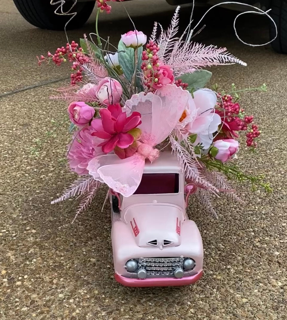 Pink Truck Floral Arrangement features a close up image of the flower arrangement and pink Chevy truck on the ground.