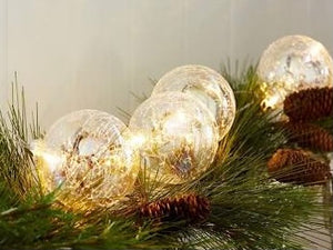 LED Glass Ball Ornaments product image features 4 glass ball LED ornaments.  Crackle finish. Strung together on one battery pack.  6 hour timer.  3AA batteries required.   Add to garlands on mantle, hall table decor, bookshelf, centerpieces and tablescapes .  Tie a few sets in your Christmas tree.  Comes as a set of 4. Great for the holidays and year round decor.  Batteries not included.