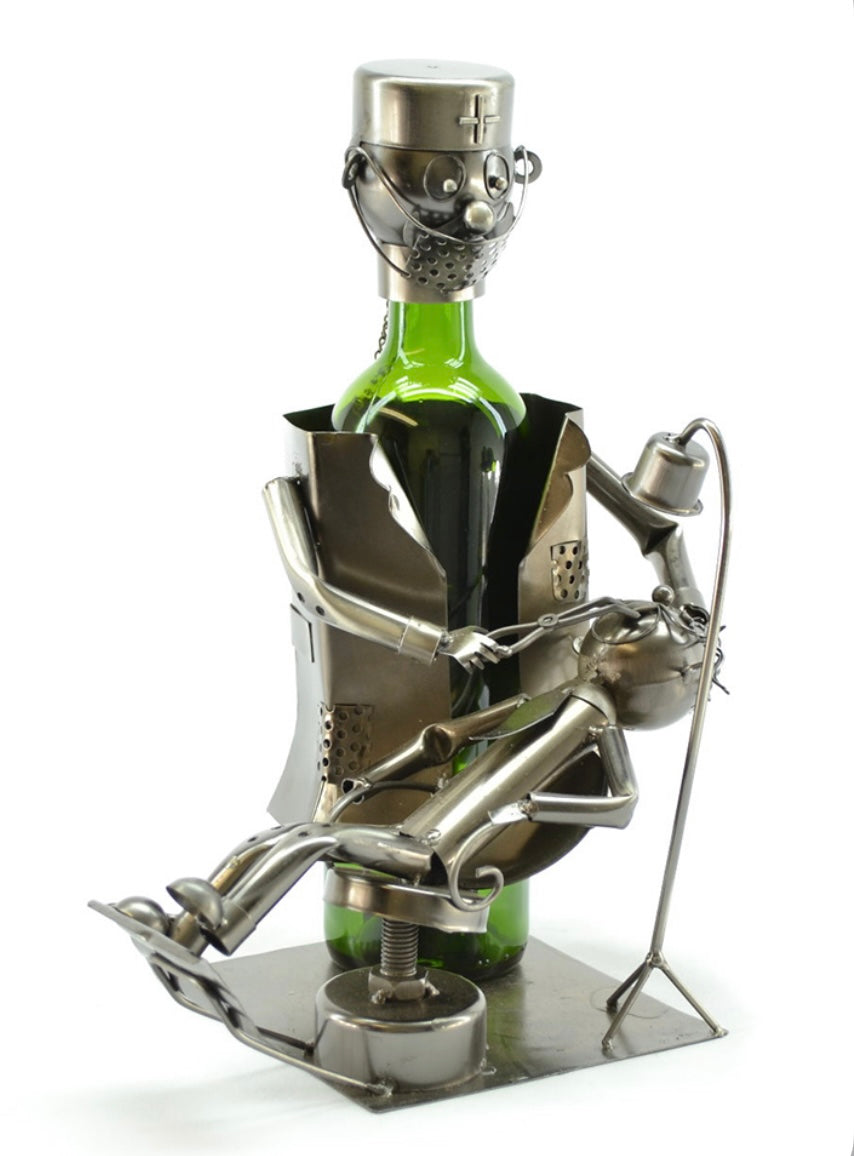 Dentist Wine Bottle Holder product image features  a dentist  bottle holder  standing over his patient.  Patient is reclined.  Recycled metal.  Color is antique silver.  Measures 13"H X 8"  W.  Holds a 750ml bottle not included.Great for displaying favorite bottled drink.drink