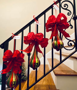 Red Green Teardrop Ornament With Bow product image features  three red and green Christmas ornaments hanging  side by side on a staircase railing.