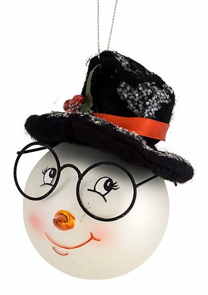 Snowman Head With Hat Glass Ornament product image features a Christmas ornament. Made of glass. Her. Wearing black rimmed spectacles and a felt top hat. Bright eyed,  eyelashes, orange nose and smiling lips. Measures 6"H. Ready to ship