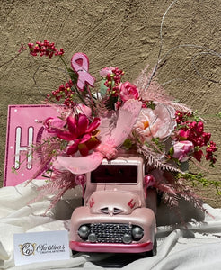 Pink Truck Floral Arrangement product image features a 1948 Chevy truck planter.  Metal truck with moving wheels.  Truck color is light pink metallic with dark pink and silver metallic highlights.  Rhinestone decorated grill.  Faux florals in various shades of pink, some greenery, feathery stems, berry picks,  willow stems, a breast cancer ribbon pick and a pink butterfly.  Pink truck measures 16" long.  Finished truck arrangement  measures 23"L x 19"W x 17"H.  Made in Memphis.  Ready to ship.